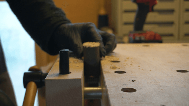 Artisan drilling a wooden rod in workshop