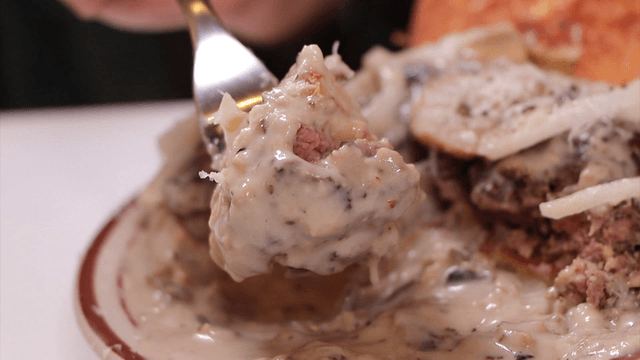 Burger dipped in cream sauce with a fork