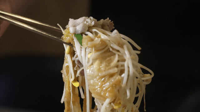 Tongs lifting kongnamul white ripened kimchi stew