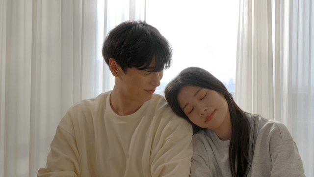 Couple sitting by window leaning on each other's shoulders