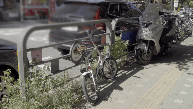 Bicycle and scooter parked on a sidewalk