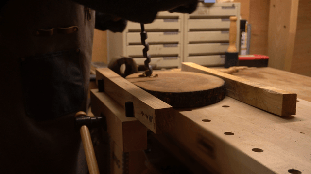 Artisan drilling a wooden board with a hand drill
