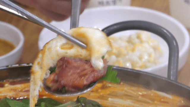 Spoon topped with pork back-bone meat and fried egg