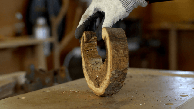 Gloved hands holding a wooden log piece