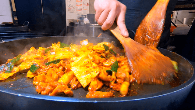 Spicy Stir-fried Chicken cooked on iron plate with spatula