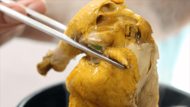 Chopsticks lifting a chicken leg from phellinus linteus ginseng chicken soup