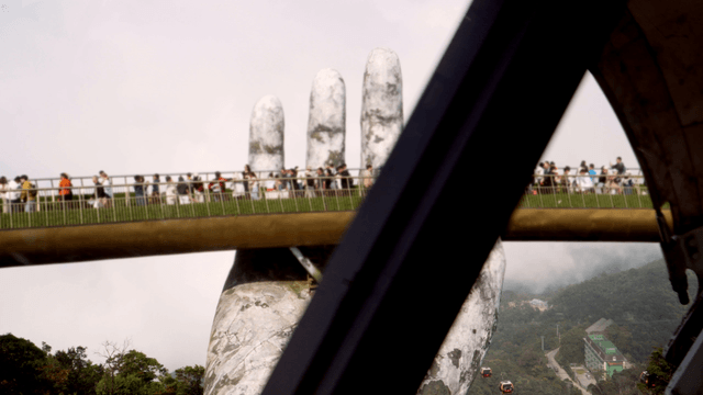 Tourists on a bridge held by giant hands