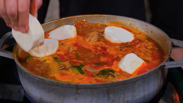 Adding cassava to the stew boiling in the pot