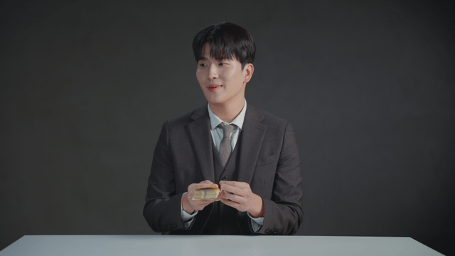 Man in a suit counting money at a desk with a satisfied expression