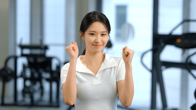 Young woman cheering with clenched fists at gym