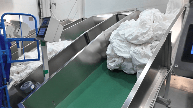 Conveyor belt carrying white fabrics in factory