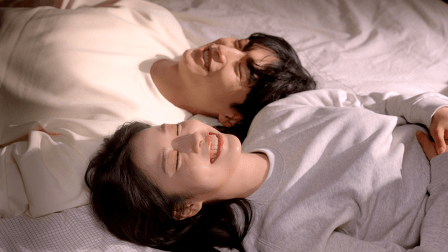 Couple lying on bed smiling with heads together