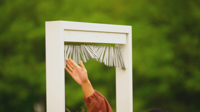 Wind chime swaying within reach in front of a green garden