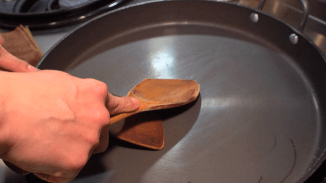 Chef practicing fried rice with wooden spatula on empty pan