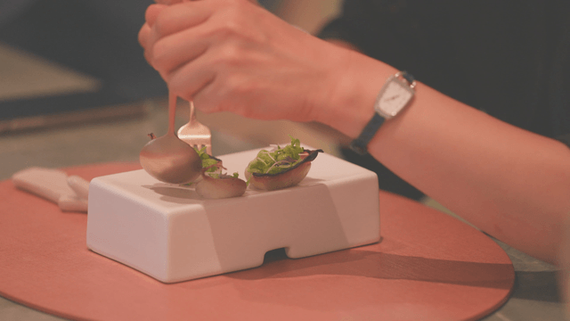 Person lifting gourmet onion dish with fork and spoon
