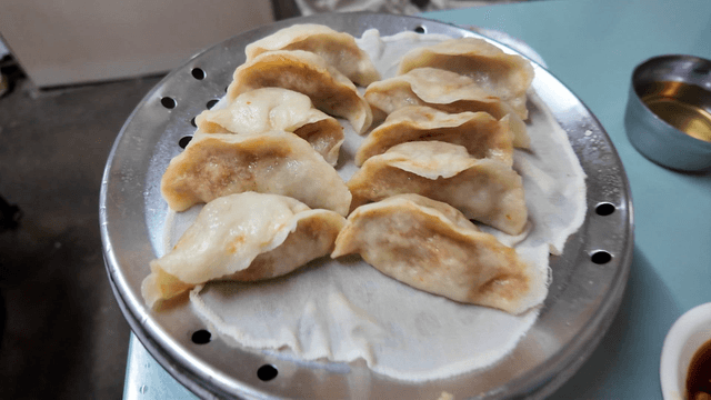 Steamed kimchi dumplings on a table with side dishes