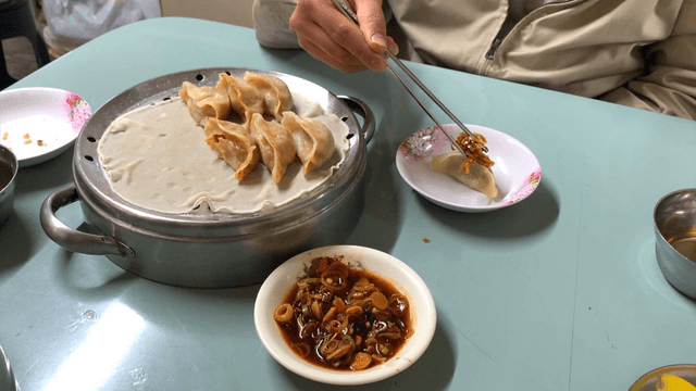 Person adding soy sauce and chopped green onions to dumplings