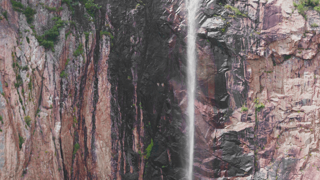 High waterfall falling along rocky cliff