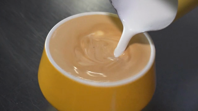 Milk being poured into a cup of coffee