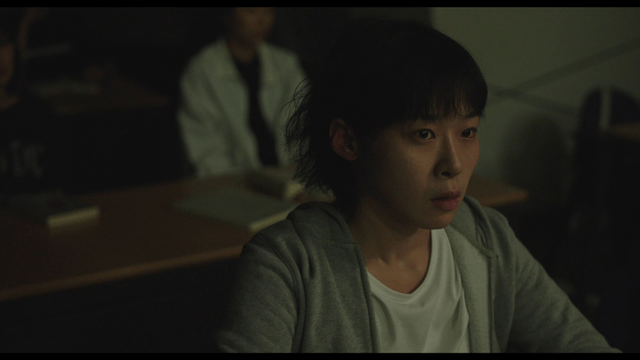 Student focused in a dimly lit classroom