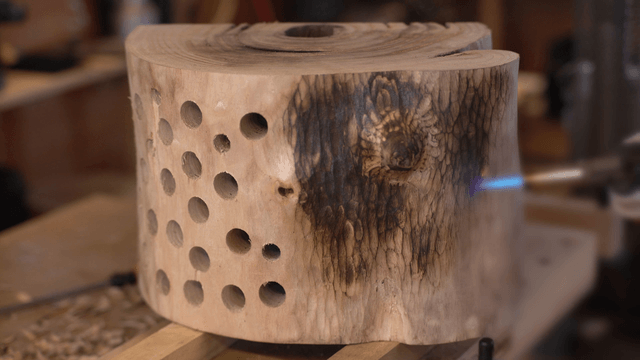 Artisan scorching the surface of a wooden sculpture with a torch