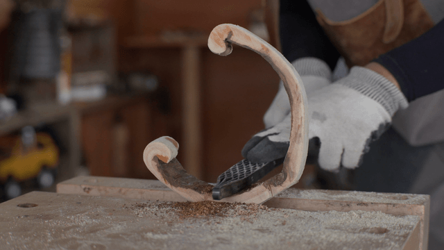 Wooden piece being refined with a rasp in workshop