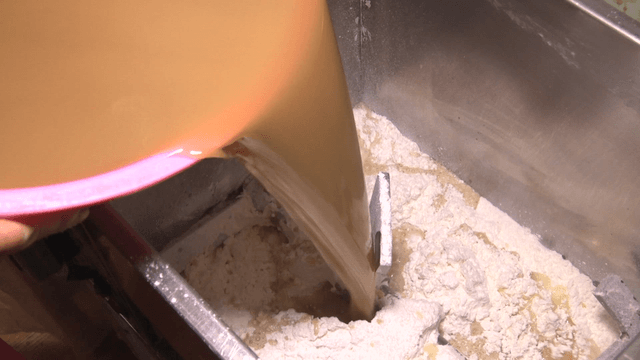 Pouring acorn liquid into a machine with flour