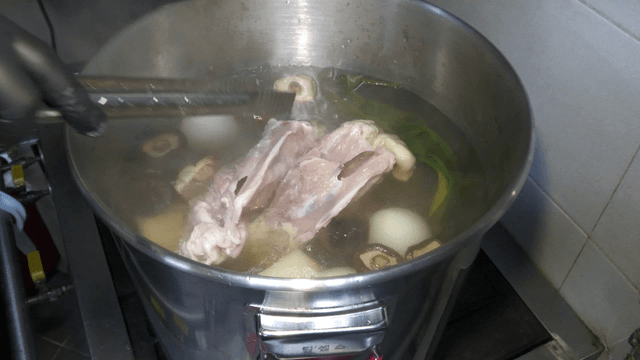 Chicken bones added to boiling broth in a large pot