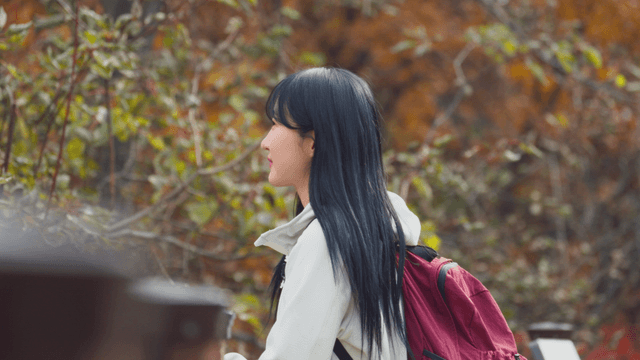 Young woman smiling at scenery in autumn park