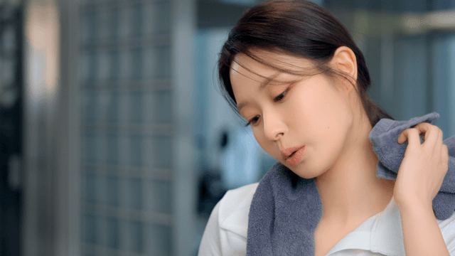 Young woman wiping sweat with a towel at gym