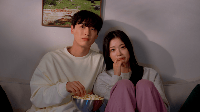 Couple watching movie at home while eating popcorn