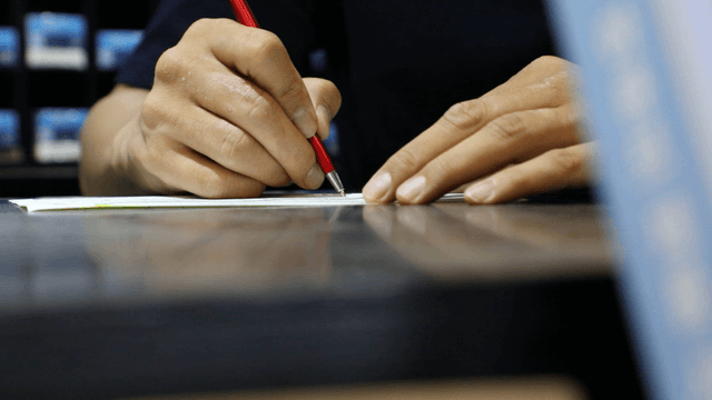 Person writing with a red pen