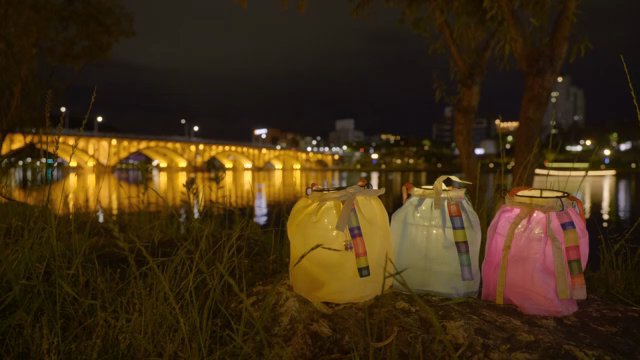 Colorful lanterns by a lit bridge at night