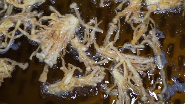 Enoki mushrooms frying in hot oil