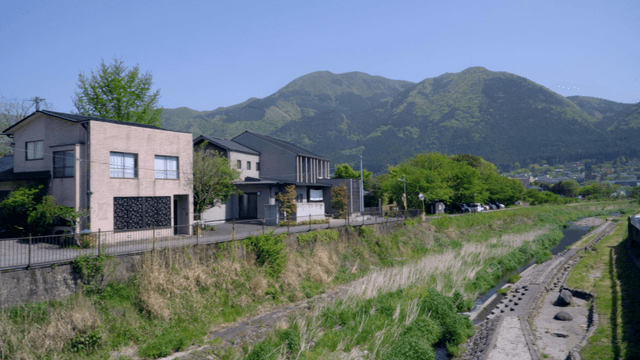 Houses by a river with mountains in the background