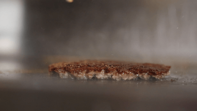 Burger patty sizzling on a hot grill