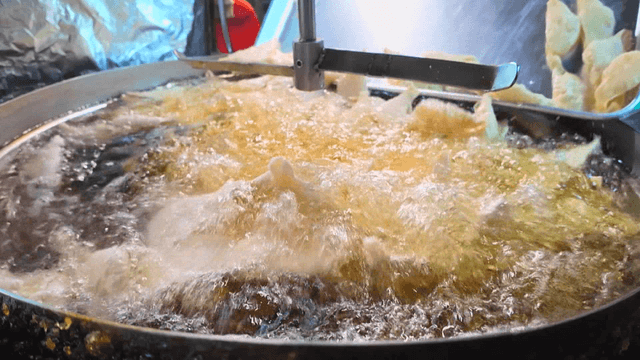 뜨거운 대형 튀김기 기름에 튀겨지는 만두