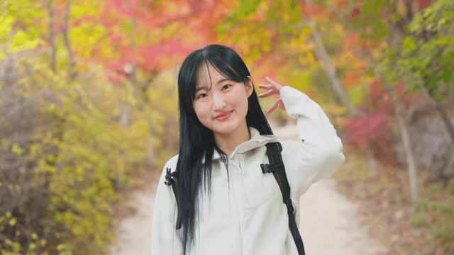 Smiling woman on autumn foliage path