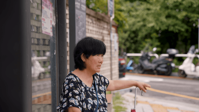 An elderly woman sitting at a bus stop