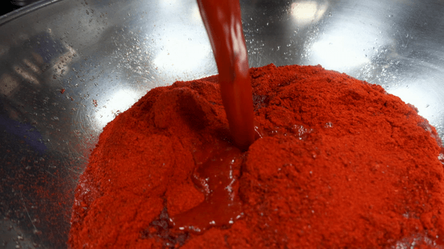 Mixing red sauce and chili powder in bowl