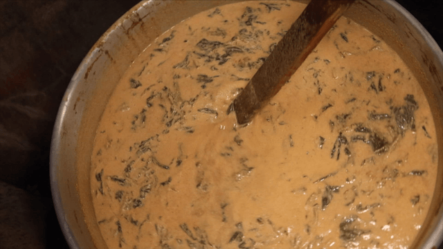 Chef stirring loach soup with a wooden ladle