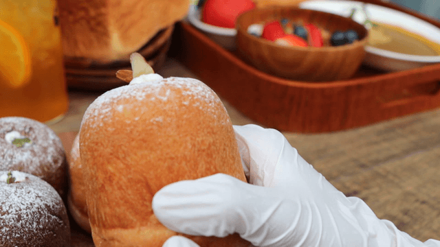 A hand holding and examining bread on a table