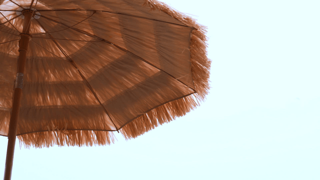 맑은 하늘 아래 밀짚 해변 파라솔