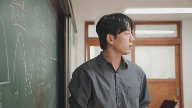 Teacher explaining math on a blackboard
