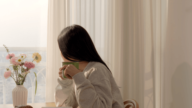 Woman enjoying peaceful morning by sunlit window