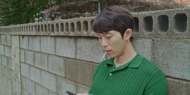 벽에 기대어 담배를 피는 남자