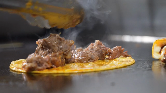 A taco being cooked on a hot griddle