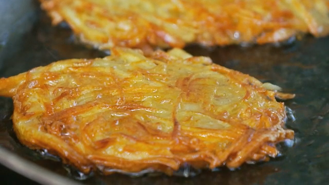 Golden potato pancakes frying in a pan