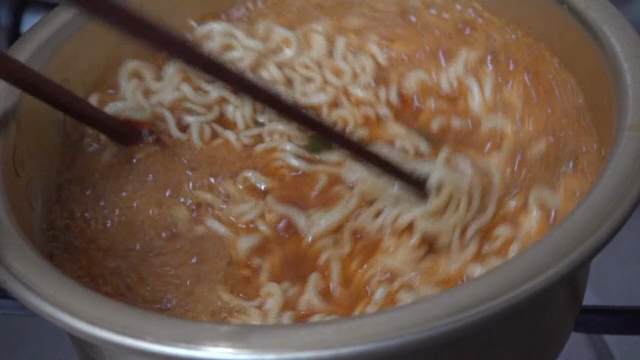 젓가락으로 저으며 끓고 있는 라면