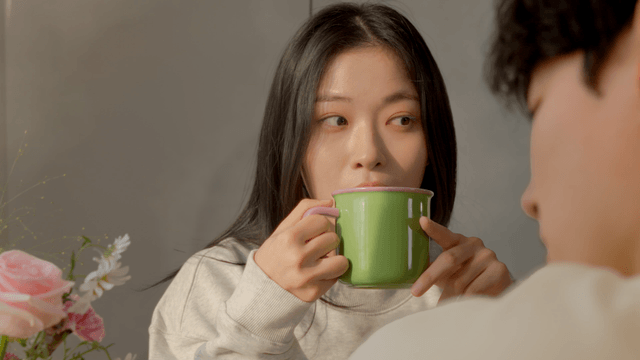 Woman enjoying warm drink in cozy home with couple
